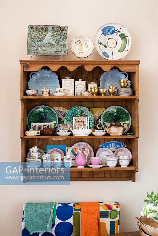 Decorative plates on wooden shelves in small eclectic kitchen  