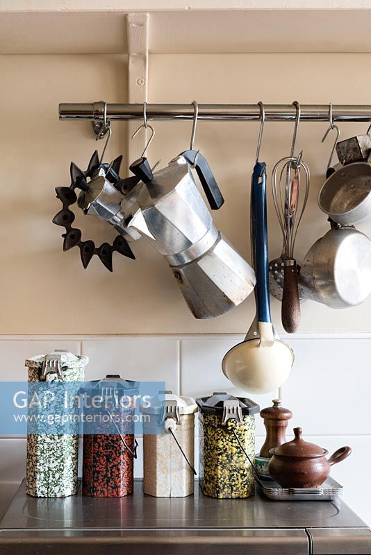 Coffee pot on hooks in kitchen above storage jars on worktop