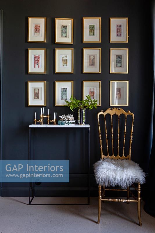 Display of framed pictures on black painted wall with console table 