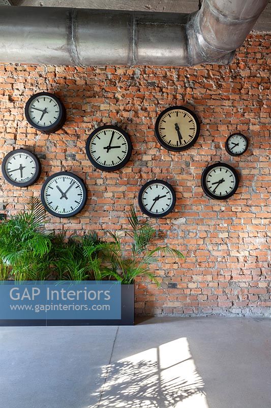 Display of clocks on exposed brick wall 