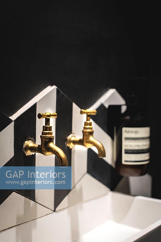 Gold taps over sink in modern black and white bathroom 