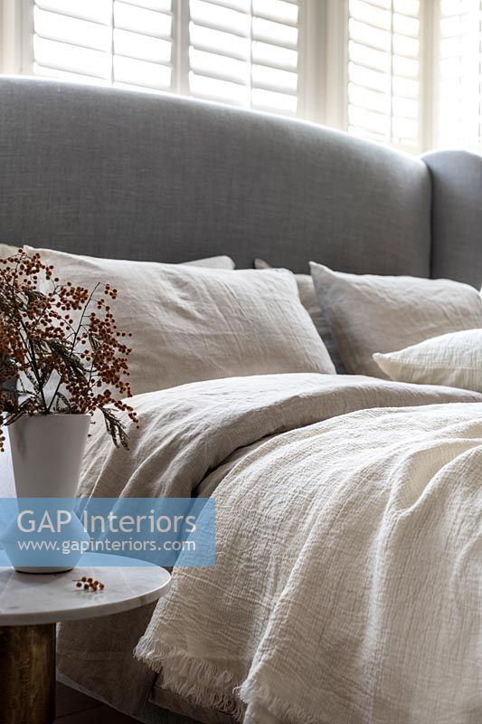 Grey upholstered headboard and linen bedding 