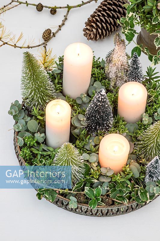 Advent arrangement with white candles, miniature fake Christmas trees