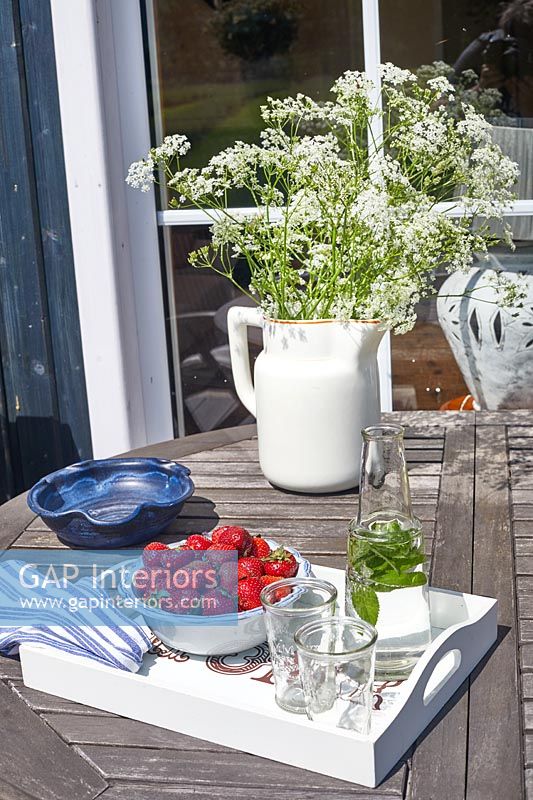Flowers in jug on wooden garden table 