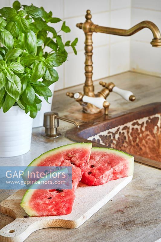 Slices of watermelon on kitchen sideboard next to sink 