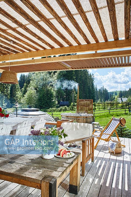 Outdoor living and dining area on decked terrace of country house in summer