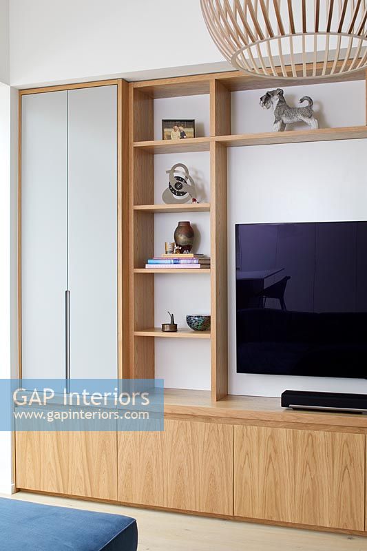 Wooden storage unit and shelves surrounding wall mounted television 
