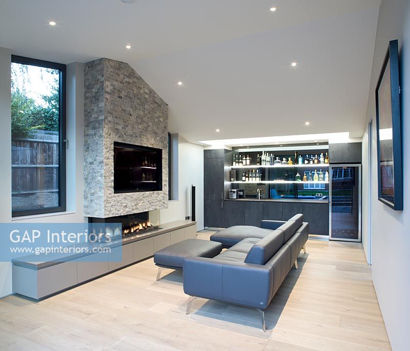 Contemporary living room with bar at one end and large television built-in to fireplace 