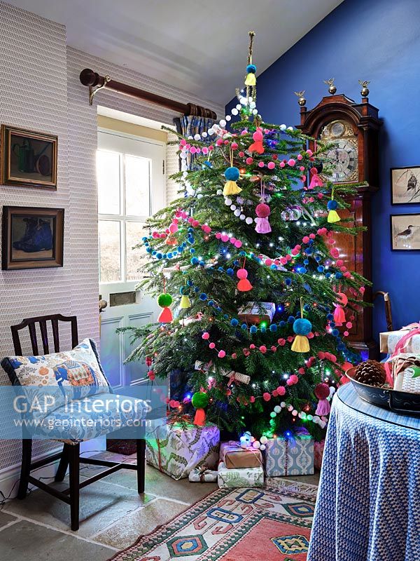 Colourful decorations on Christmas tree in country living room 