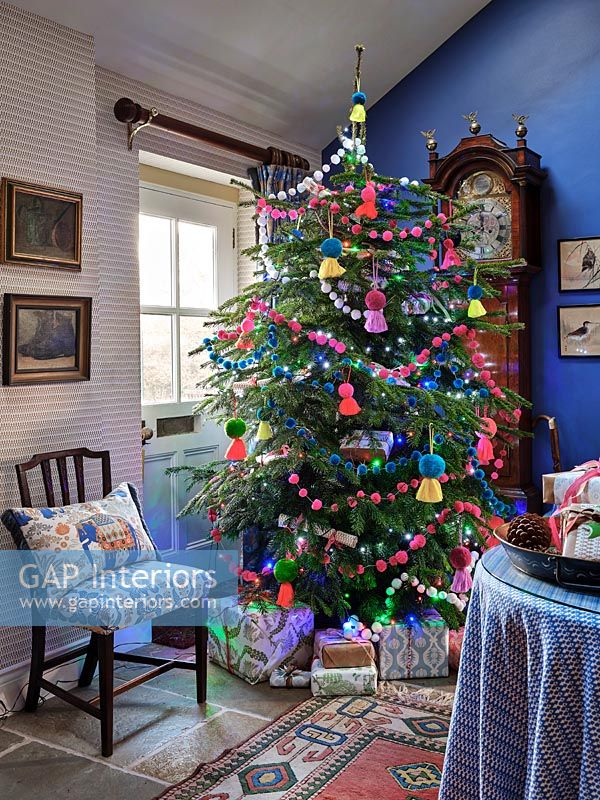 Colourful decorations on Christmas tree in country living room 
