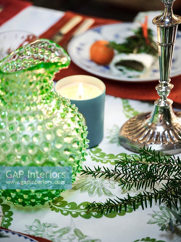 Detail of dining table with textured glass jug and silver candlestick 