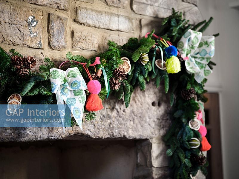 Detail of Christmas garland on stone fireplace surround 