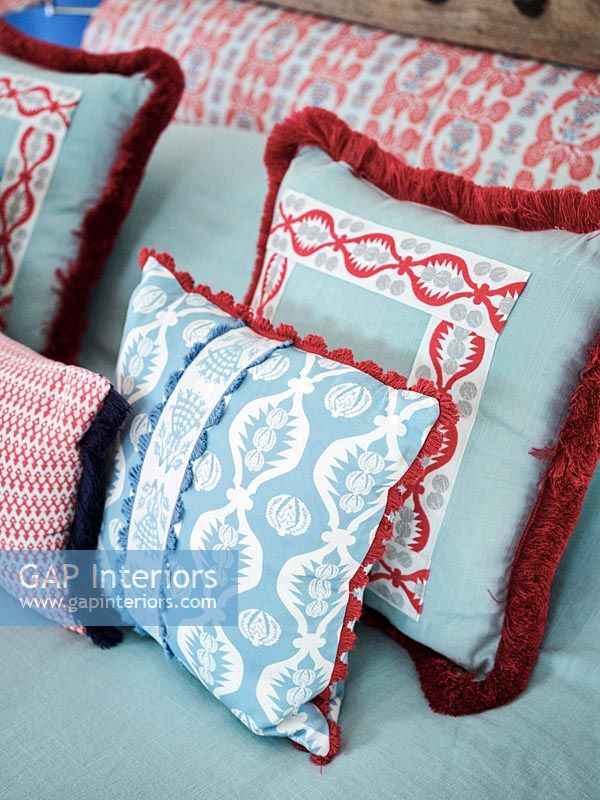 Blue and red patterned cushions and headboard in country bedroom 