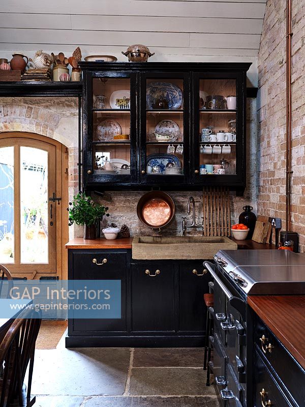 Country kitchen with exposed brickwork and black painted units 