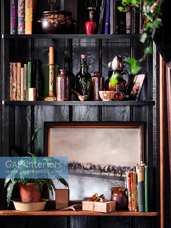 Detail of shelves against black painted wooden wall 