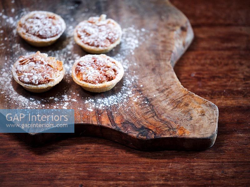 Detail of mince pies on wooden chopping board 