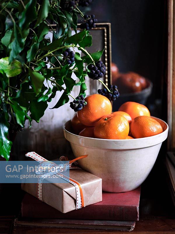 Christmas gifts next to fruit bowl filled with satsumas 