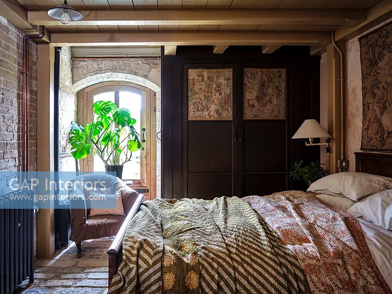 Country bedroom with decorative panels on dividing wooden screen 