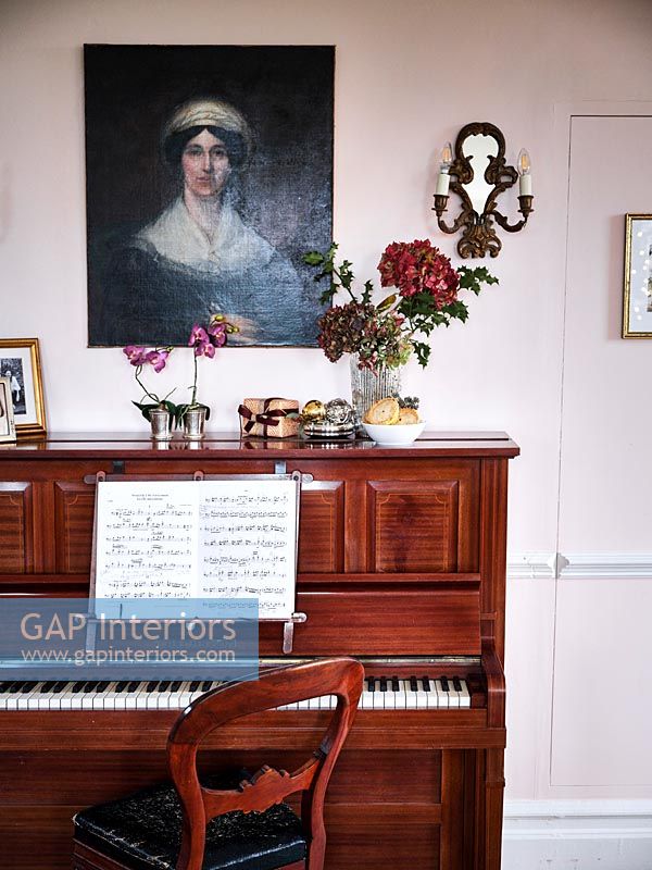 Portrait hanging above an upright piano 
