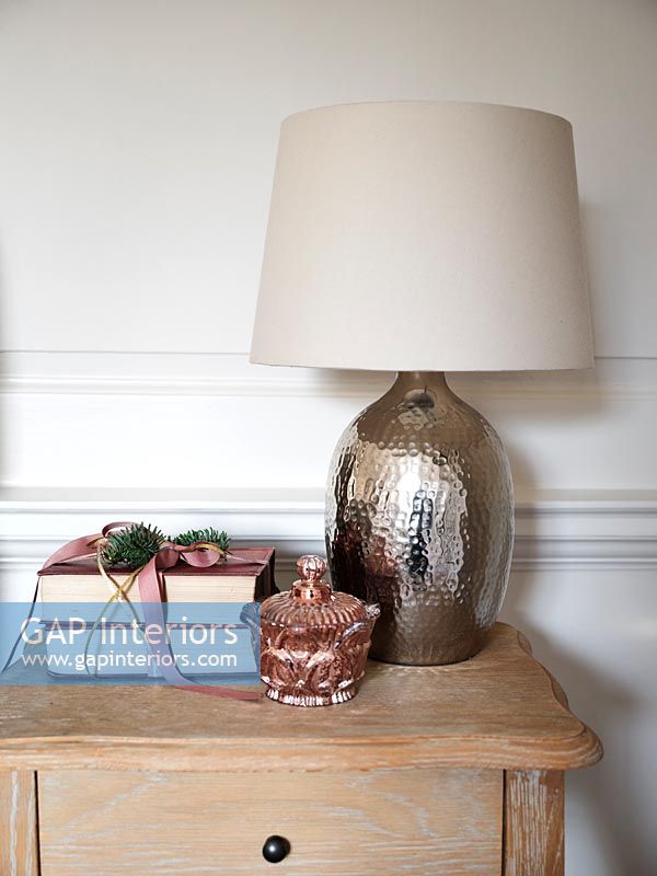 Metallic lamp on bedside table with books wrapped as Christmas gift