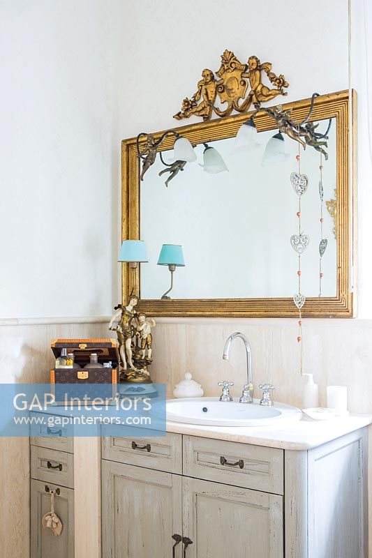Gilded mirror above bathroom sink unit 