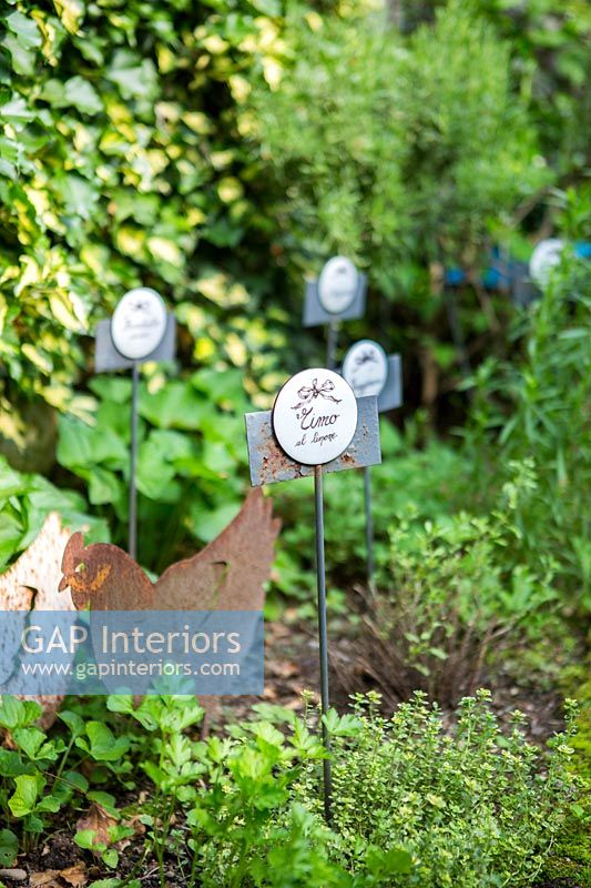 Decorative plant labels and chicken ornaments in herb garden 