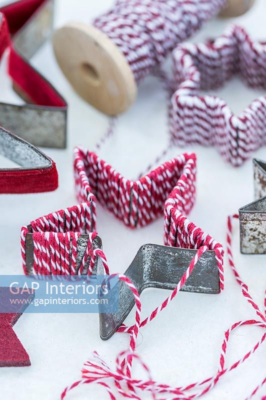 Metal cookie cutter covered with red and white string
