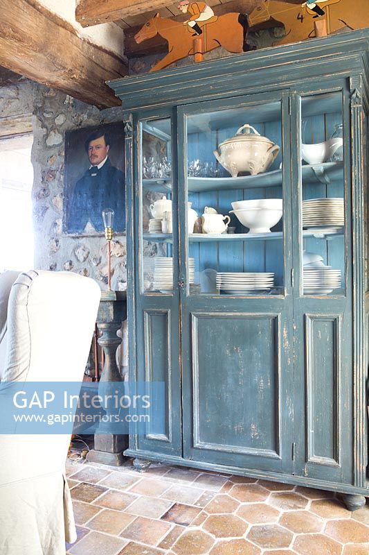 Painted dresser filled with crockery in country living room 
