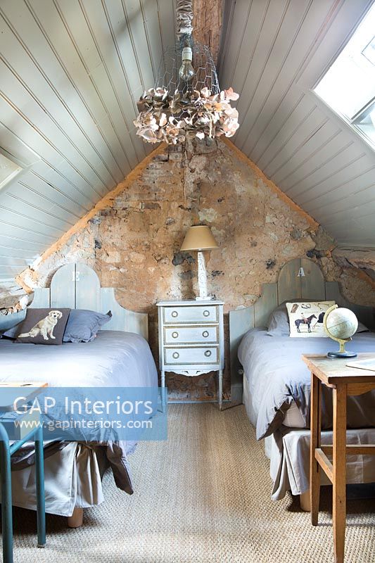 Exposed stone wall and pitched roof in modern country twin bedroom 