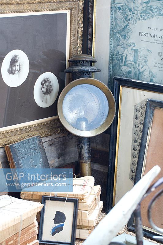 Detail of antique carriage lamp among framed paintings and books 