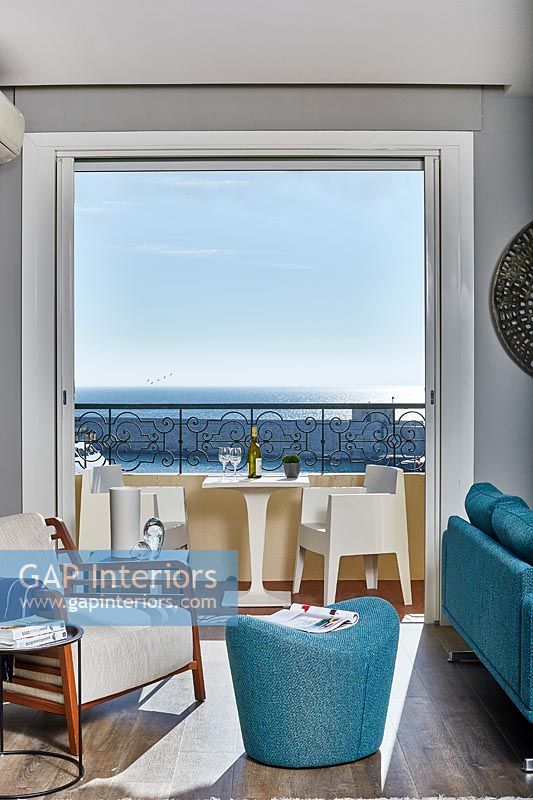 Modern living room with sea view thorugh open French windows 