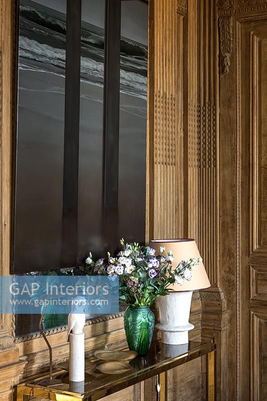 Flowers in vase on console table with wooden panelled walls 