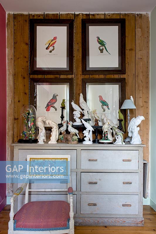 Display of bird themed paintings and ornaments above chest of drawers 