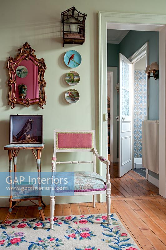 Vintage chair and ornaments next to green painted wall 
