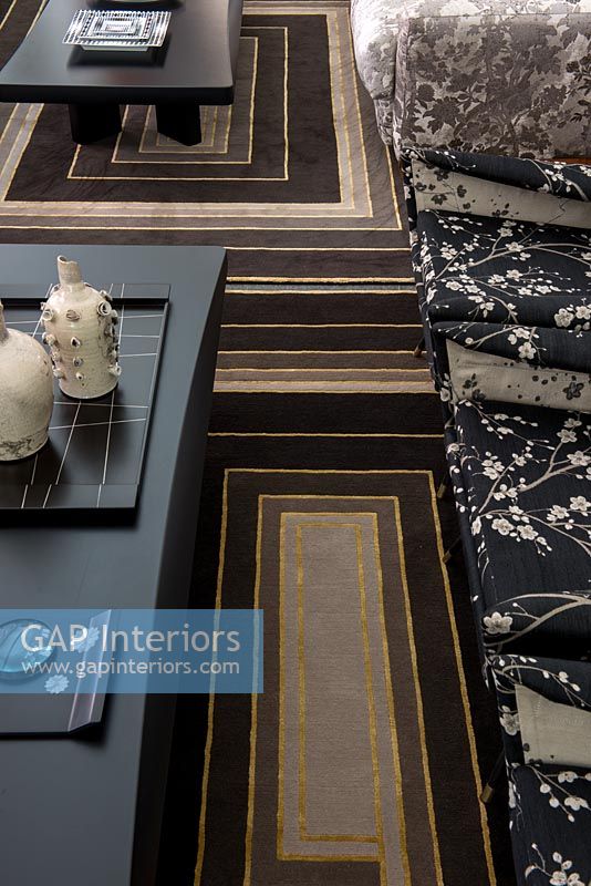Black and gold patterned carpet between sofa and coffee table