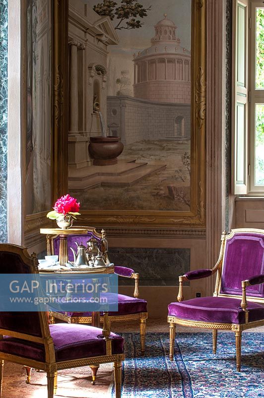 Purple antique chairs with huge painting on wall in class living room 