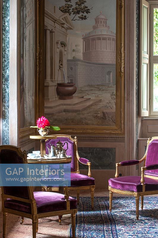 Purple antique chairs with huge painting on wall in class living room 