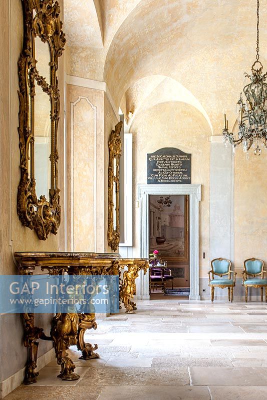 Pair of gilded console tables with mirrors in classic hallway 