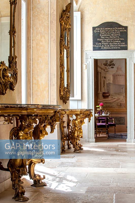 Pair of gilded console tables with mirrors in classic hallway 