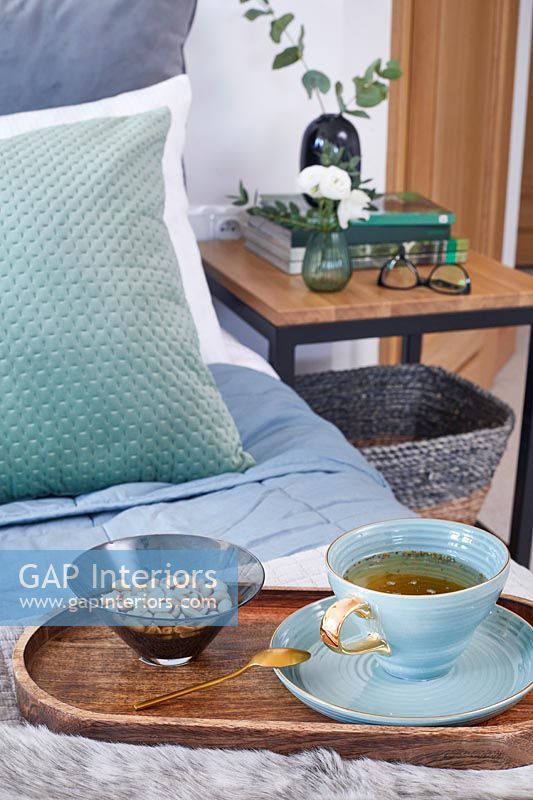 Tray with drink and snacks on modern bed 