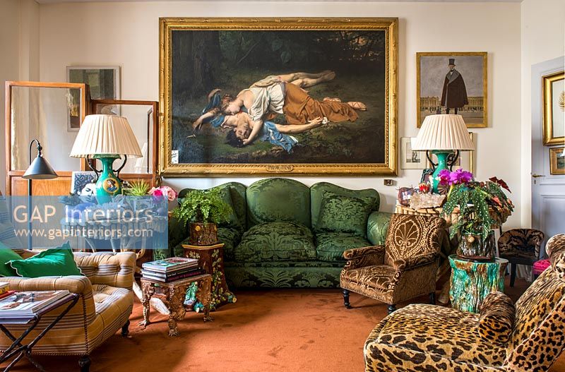 Large classic painting above green velvet sofa in eclectic living room 