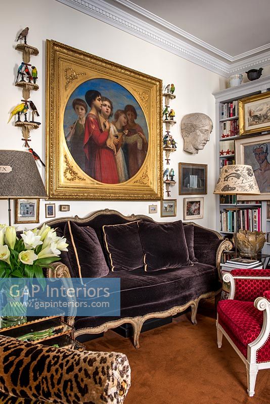 Large classic painting above brown velvet sofa in eclectic living room 