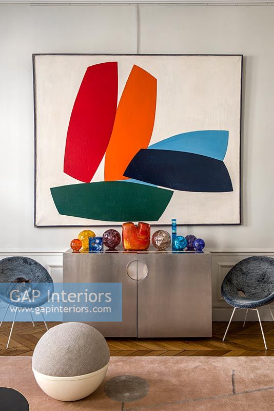 Colourful artwork on wall above modern sideboard 