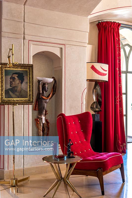 Red velvet chair in modern living room with classic painting and sculpture