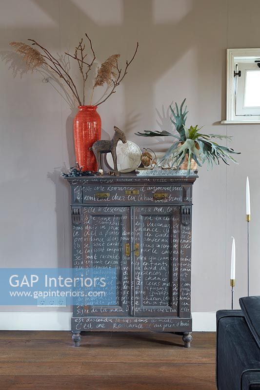 Grey painted wooden unit decorated with white writing 
