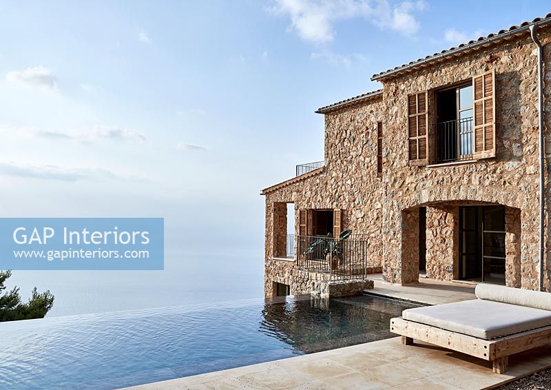 Stone coastal house exterior with infinity pool and sea views 