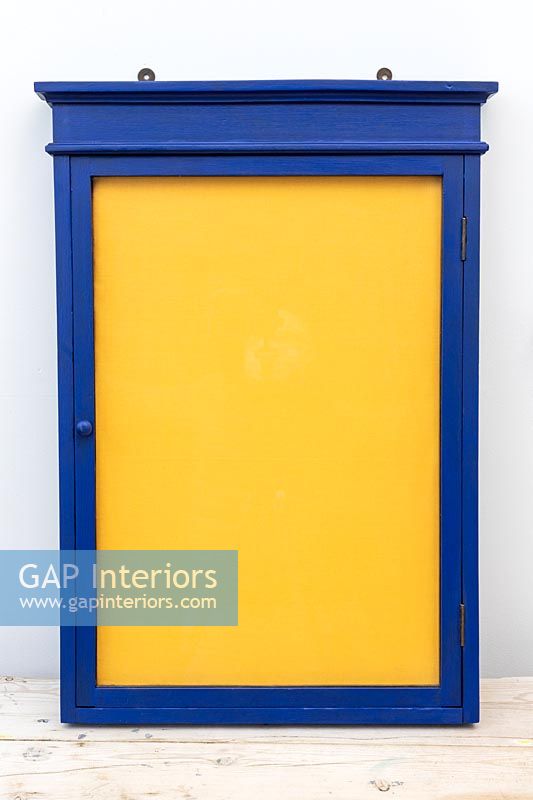 Painted blue wooden frame with yellow fabric covered corkboard