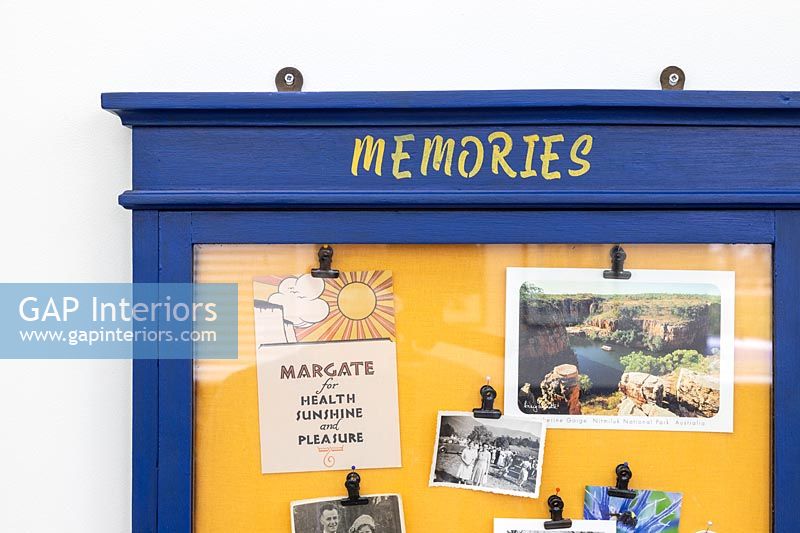 Blue and yellow memories notice board on wall 
