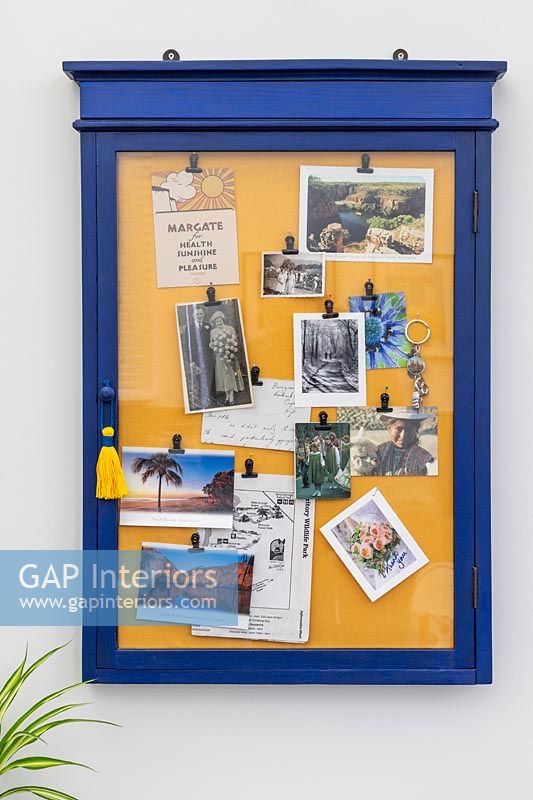 Blue and yellow framed notice board on wall 