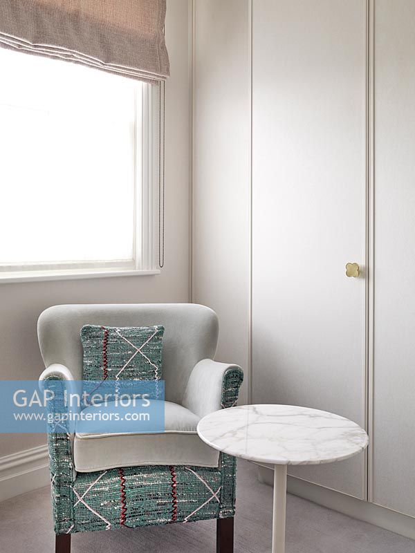 Patterned armchair and small side table in dressing room 